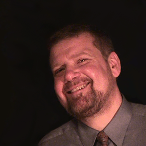 Rich Grzesiak sitting behind a desk taking a moment to look up from his work toward the camera.